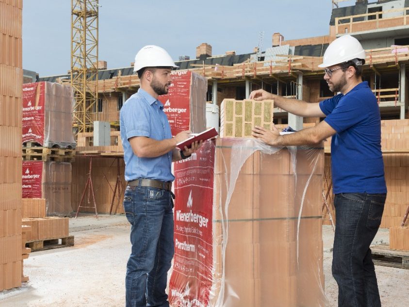 Building professionals on construction site talking about insulation filled clay block