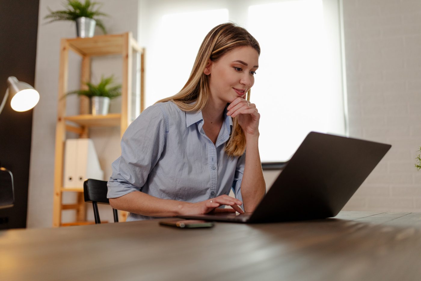 Close up photo of young smiling designer working on laptop at home office.