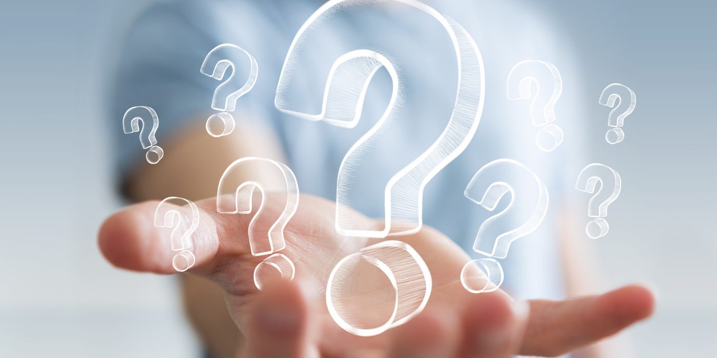 Businessman on blurred background holding hand drawn question marks