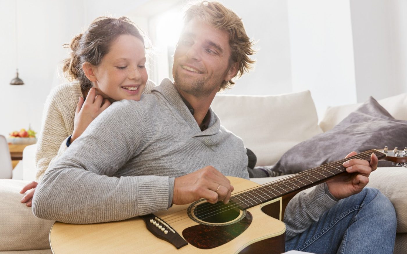 Girl listens to man playing guitar