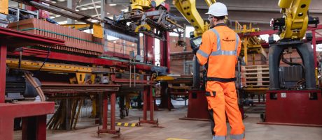 Factory worker operating robotic arm with remote control unit