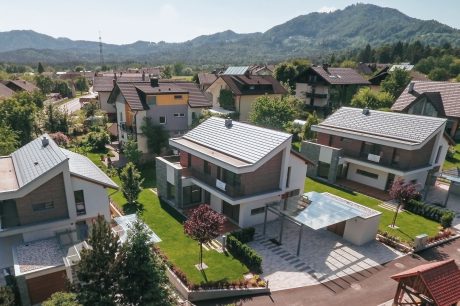 Zračni pogled na tri kuće s uređenim vrtovima i brežuljcima u pozadini, referentni projekt Kuća Tri Hise.