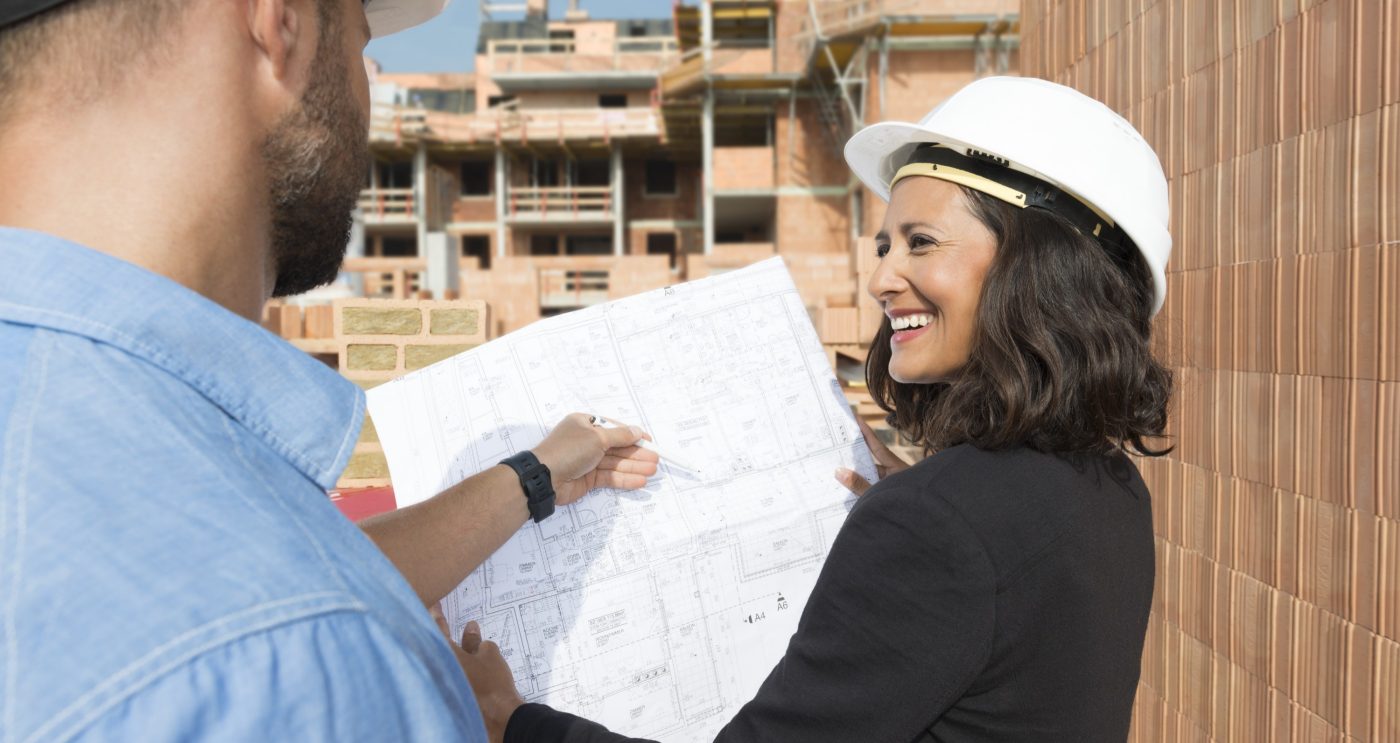 Male and female Architect with technical drawing on construction site