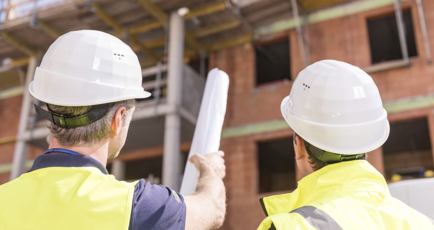 Builder pointing at building shell with blueprint