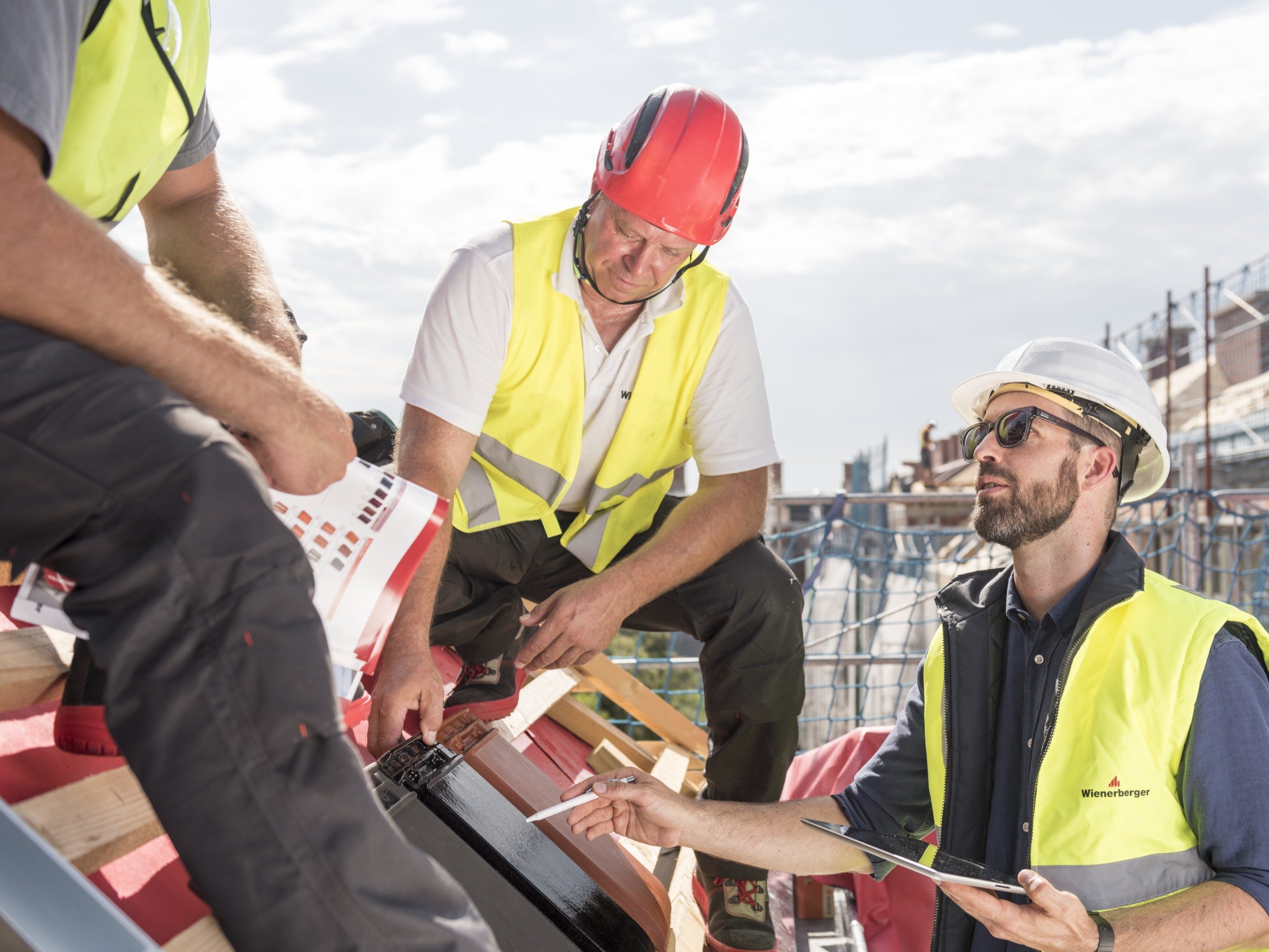 Product manager explaining product advantages to urban roofers wearing safety jackets and hard hats