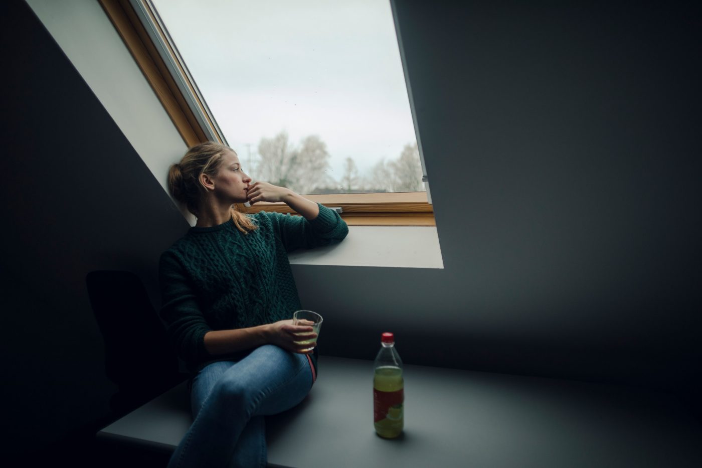 Young woman looking out of attic window