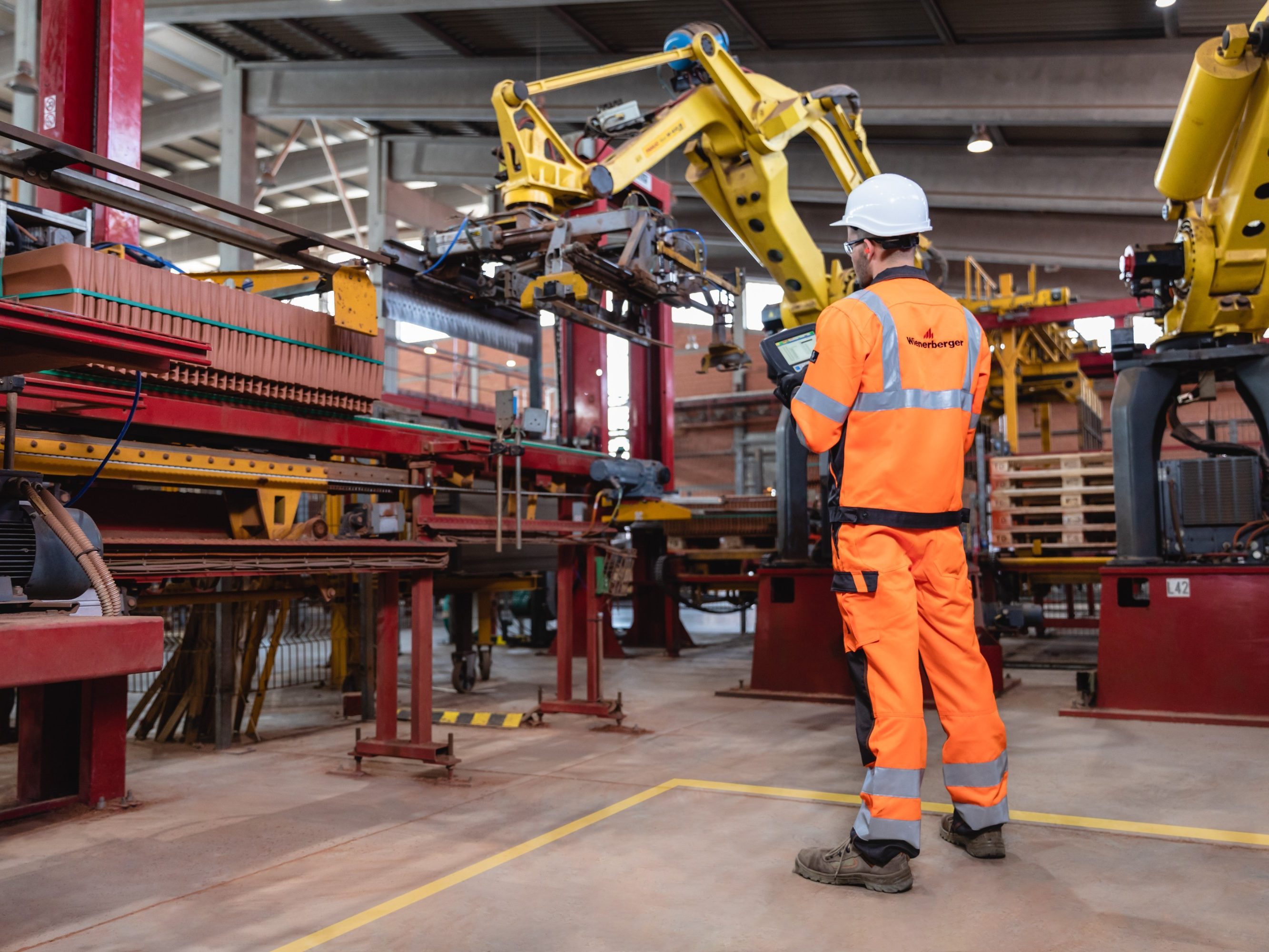 Factory worker operating robotic arm with remote control unit