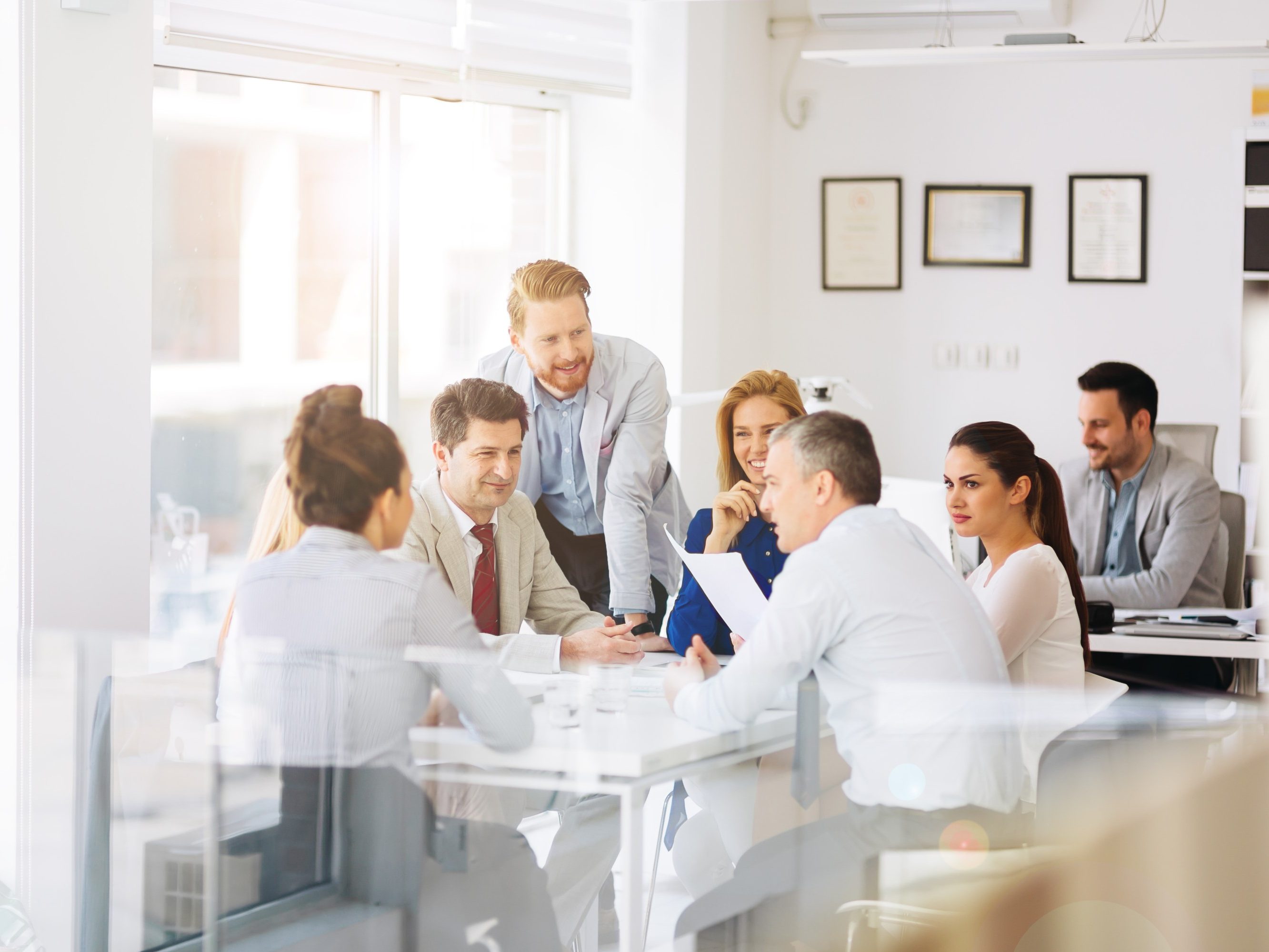 Female and male managers sitting at table talking about presentation chart on TV-screen
