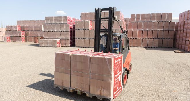 Forklift loads clay block pallets on tuck on stockyard