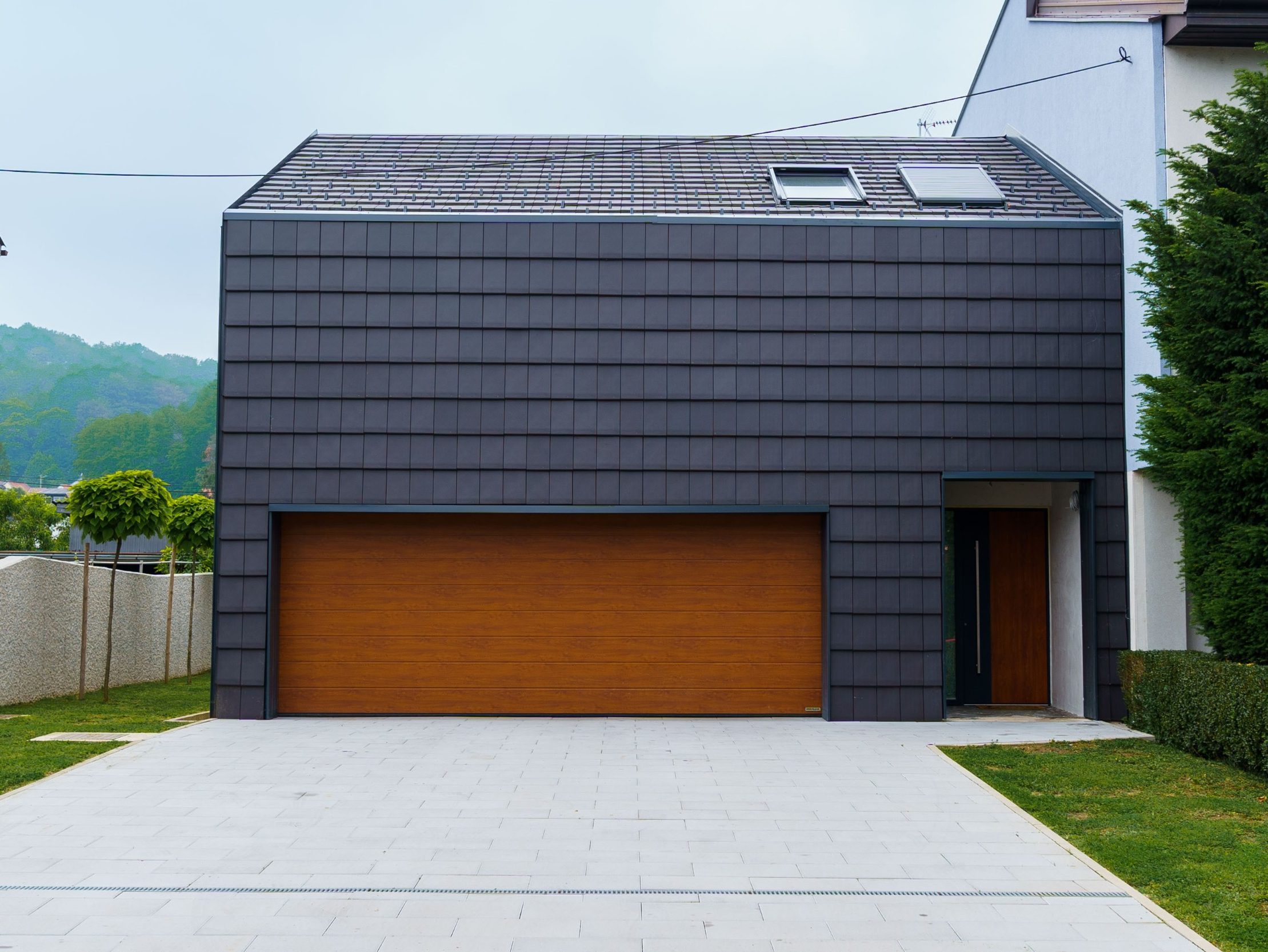 Moderna kuća s ravnim antracit crijepom na krovu i fasadi i smeđim garažnim vratima imitacije drveta