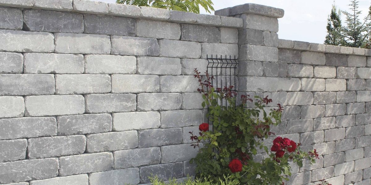 Semmelrock zid, zidni blokovi sive boje s teksturiranom površinom - vanjska ograda s stupovima uz crvene ruže