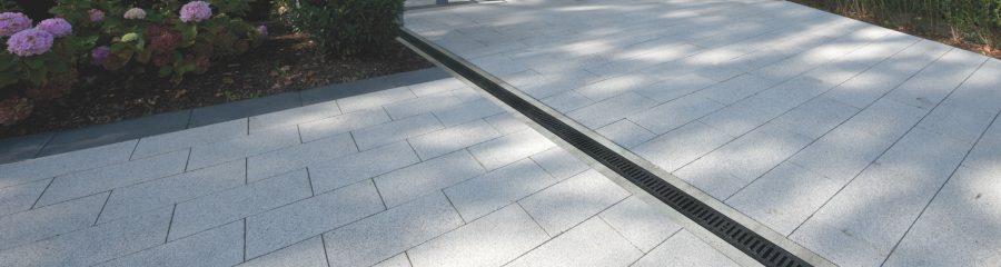 Semmelrock svijetlosivi betonski opločnici na prilazu moderne obiteljske kuće s garažom i ugrađenom SemDrain kanalicu za odvodnju oborinske vode