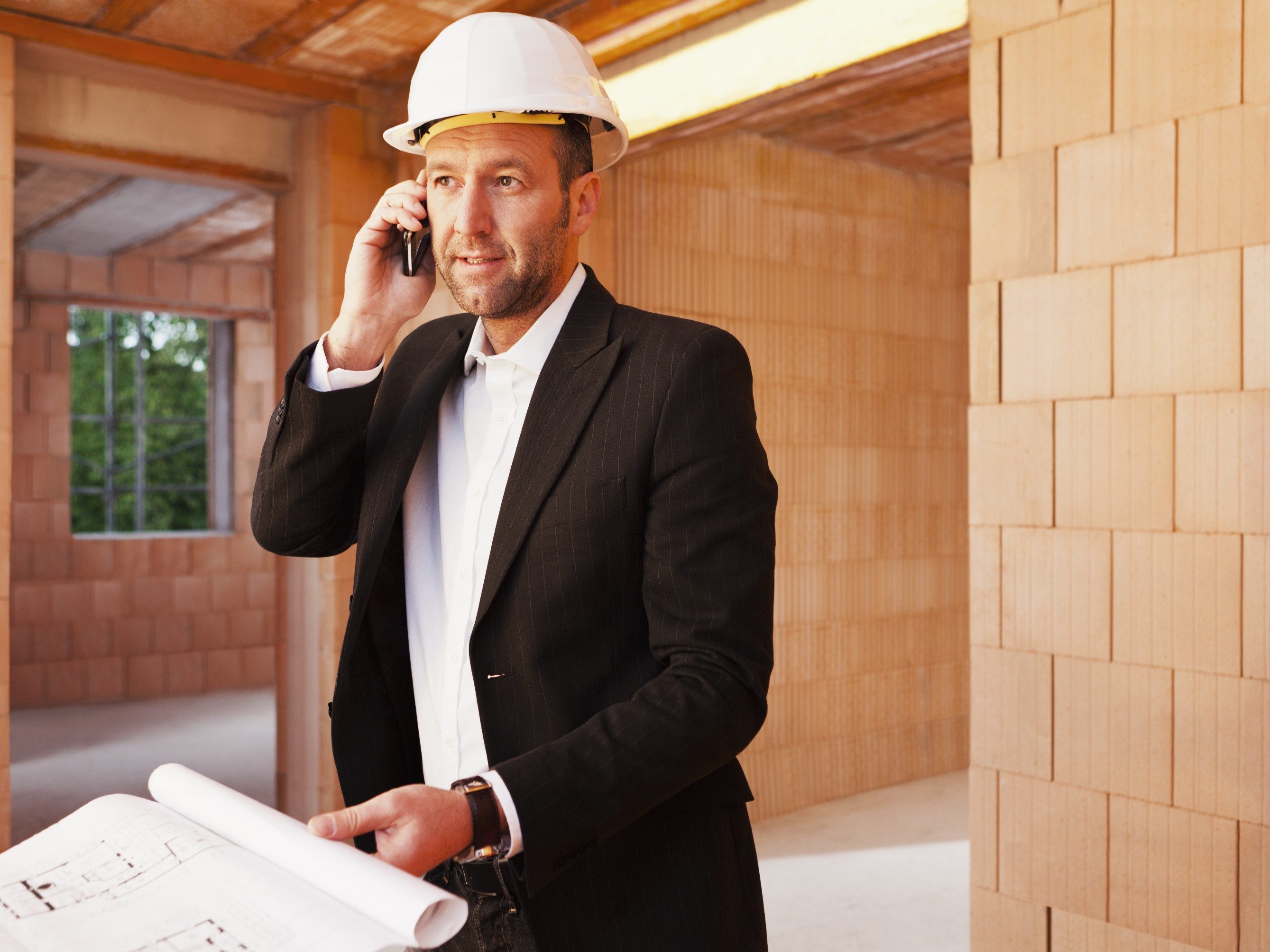 Building professional with mobile phone and blueprint inside building-shell