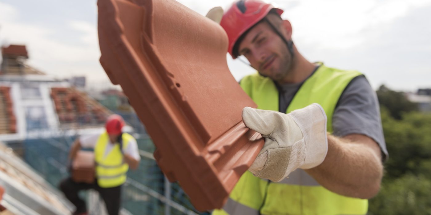 Urban roofers showing product installation roof tiles construction worker wearing hard hat