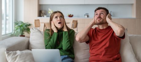 Djevojka koja prekriva uši jastukom zbog prevelike buke u stanu